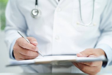 Asyalı doktor, hastaları tedavi etmek için araştırma yöntemi ve teknikle ilgili belgeleri inceliyor..