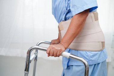 Asya baş ağrısı. Esnek destek kemeri takıp yürüteç takıyor..