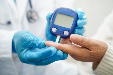 Diyabet tedavisinde kan şekeri seviyesini kontrol etmek için dijital glikoz ölçer kullanan Asyalı doktor.