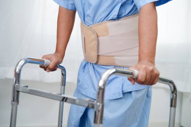 Asya baş ağrısı. Esnek destek kemeri takıp yürüteç takıyor..