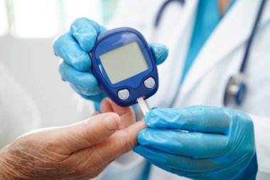Diyabet tedavisinde kan şekeri seviyesini kontrol etmek için dijital glikoz ölçer kullanan Asyalı doktor.