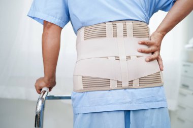 Asya baş ağrısı. Esnek destek kemeri takıp yürüteç takıyor..