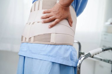 Asya baş ağrısı. Esnek destek kemeri takıp yürüteç takıyor..