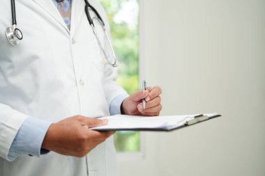 Doktor kontrol ediyor ve teşhis ilacını hastanedeki hastaların dosyalarına not ediyor..