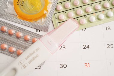 Doğum kontrol haplarıyla hamilelik testi ve takvimde kadınlar için prezervatif, yumurtlama günü.
