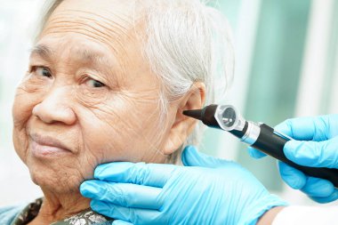 Otolaryngologist ya da ENT hekim doktoru yaşlı hasta kulağını otoskopla muayene ediyor, işitme sorunu var.. 