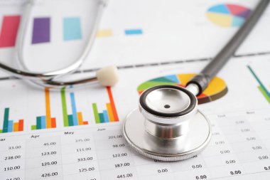 Çizelge ya da grafik kağıdı, Finansal, hesap, istatistik ve iş verileri medikal sağlık kavramı üzerine steteskop ve ABD doları banknotları.