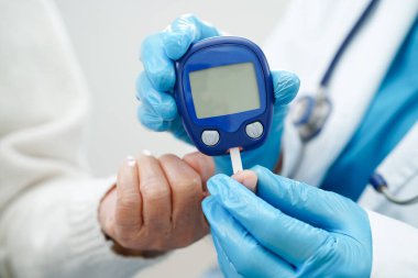Diyabet tedavisinde kan şekeri seviyesini kontrol etmek için dijital glikoz ölçer kullanan Asyalı doktor.
