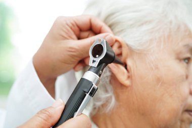 Otolaryngologist ya da ENT hekim doktoru yaşlı hasta kulağını otoskopla muayene ediyor, işitme sorunu var.. 