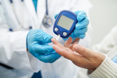 Diyabet tedavisinde kan şekeri seviyesini kontrol etmek için dijital glikoz ölçer kullanan Asyalı doktor.