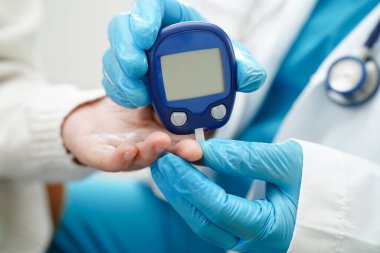 Diyabet tedavisinde kan şekeri seviyesini kontrol etmek için dijital glikoz ölçer kullanan Asyalı doktor.