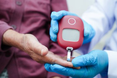 Diyabet tedavisinde kan şekeri seviyesini kontrol etmek için dijital glikoz ölçer kullanan Asyalı doktor.