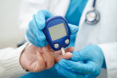 Diyabet tedavisinde kan şekeri seviyesini kontrol etmek için dijital glikoz ölçer kullanan Asyalı doktor.