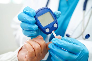 Diyabet tedavisinde kan şekeri seviyesini kontrol etmek için dijital glikoz ölçer kullanan Asyalı doktor.