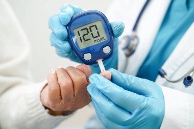 Diyabet tedavisinde kan şekeri seviyesini kontrol etmek için dijital glikoz ölçer kullanan Asyalı doktor.