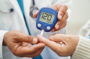 Diyabet tedavisinde kan şekeri seviyesini kontrol etmek için dijital glikoz ölçer kullanan Asyalı doktor.