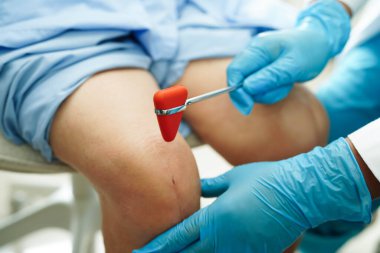 Asyalı doktor, hastanedeki yaşlı hastayı muayene etmek için diz refleksi sinirine vurdu..