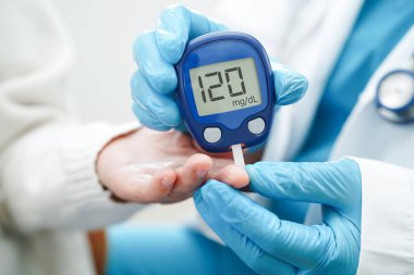 Diyabet tedavisinde kan şekeri seviyesini kontrol etmek için dijital glikoz ölçer kullanan Asyalı doktor.