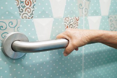 Asyalı yaşlı kadın hasta tuvalette tuvalet desteğini, tırabzan emniyet çubuğunu, hemşire hastanesinde güvenliği kullanıyor..