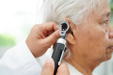 Otolaryngologist ya da ENT hekim doktoru yaşlı hasta kulağını otoskopla muayene ediyor, işitme sorunu var..