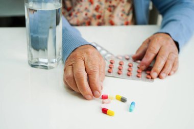 Asyalı yaşlı kadın bardakta suyla birlikte hap tutuyor. Sağlıklı, güçlü bir ilaç..