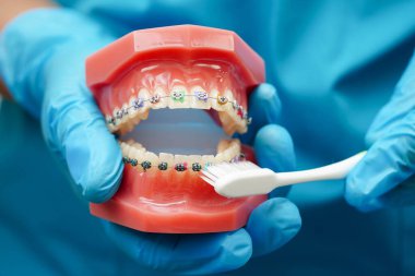 Diş fırçasıyla dişleri temizleyen doktor hasta ve dişçiye diş hekimliği dersi veriyor..