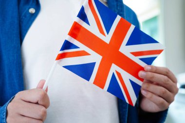 İngilizce öğren, Asyalı ergen öğrenci okulda bayraklı kitap tutuyor..