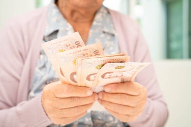 Retired elderly woman counting coins money and worry about monthly expenses and treatment fee payment.