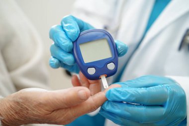 Diyabet tedavisinde kan şekeri seviyesini kontrol etmek için dijital glikoz ölçer kullanan Asyalı doktor.