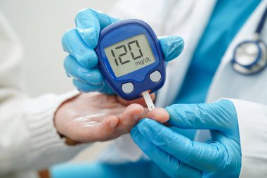 Diyabet tedavisinde kan şekeri seviyesini kontrol etmek için dijital glikoz ölçer kullanan Asyalı doktor.