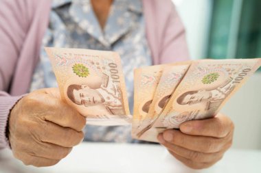 Retired elderly woman counting coins money and worry about monthly expenses and treatment fee payment.