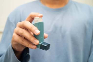 Astım ve kronik obstrüktif akciğer hastalığı COPD, Asyalı genç adam ölçülü doz solunum cihazı kullanıyor..