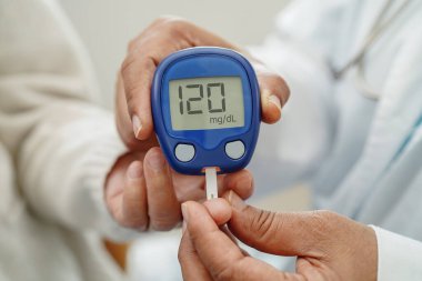 Diyabet tedavisinde kan şekeri seviyesini kontrol etmek için dijital glikoz ölçer kullanan Asyalı doktor.