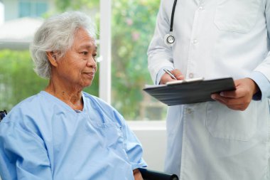 Klinikteki yaşlı kadın hastalarla ilgilenen, yardım eden ve onları cesaretlendiren doktor..