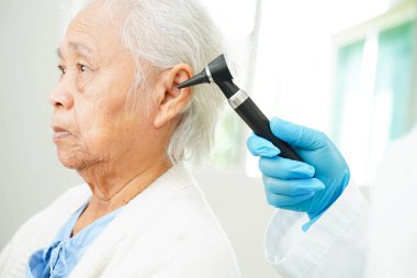 Otolaryngologist ya da ENT hekim doktoru yaşlı hasta kulağını otoskopla muayene ediyor, işitme sorunu var..