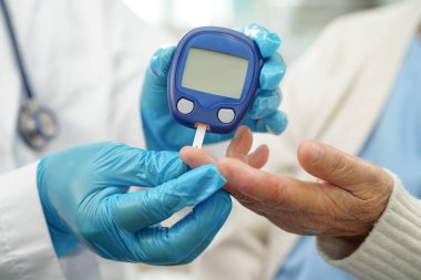 Diyabet tedavisinde kan şekeri seviyesini kontrol etmek için dijital glikoz ölçer kullanan Asyalı doktor.