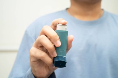 Astım ve kronik obstrüktif akciğer hastalığı COPD, Asyalı genç adam ölçülü doz solunum cihazı kullanıyor..