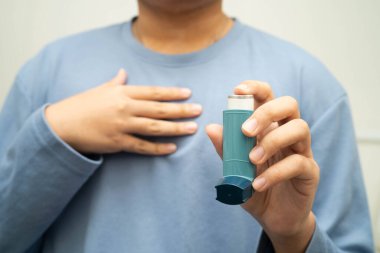 Astım ve kronik obstrüktif akciğer hastalığı COPD, Asyalı genç adam ölçülü doz solunum cihazı kullanıyor..