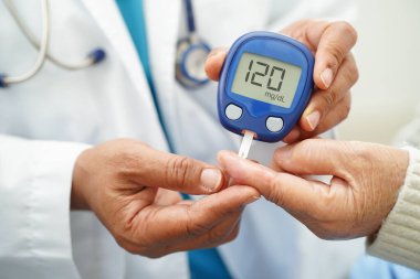 Diyabet tedavisinde kan şekeri seviyesini kontrol etmek için dijital glikoz ölçer kullanan Asyalı doktor.