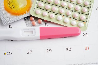 Doğum kontrol haplarıyla hamilelik testi ve takvimde kadınlar için prezervatif, yumurtlama günü.