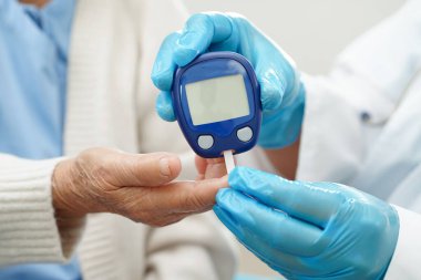 Diyabet tedavisinde kan şekeri seviyesini kontrol etmek için dijital glikoz ölçer kullanan Asyalı doktor.