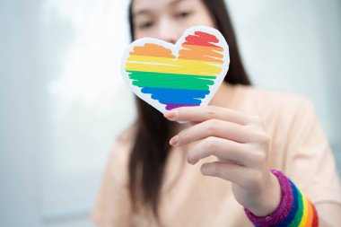 Gökkuşağı bayrağıyla LGBT kalbini tutan Asyalı kadın.