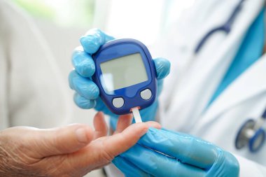 Diyabet tedavisinde kan şekeri seviyesini kontrol etmek için dijital glikoz ölçer kullanan Asyalı doktor.