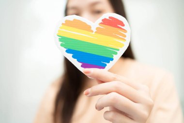 Gökkuşağı bayrağıyla LGBT kalbini tutan Asyalı kadın.