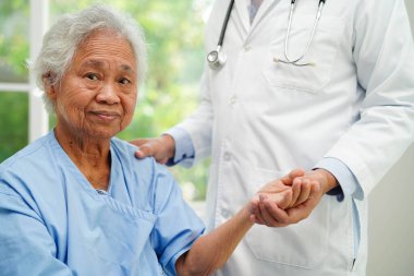 Klinikteki yaşlı kadın hastalarla ilgilenen, yardım eden ve onları cesaretlendiren doktor..