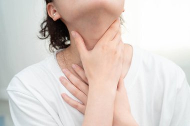 Tiroit bezi sorunu için boynuna ve boğazına dokunan Asyalı kadın..