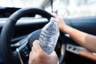 Asyalı kadın sürücü arabada soğuk su tutuyor, tehlikeli ve kaza riski var..