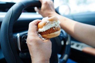 Asyalı kadın sürücü arabada hamburger yiyip, tutar, tehlikeli ve kaza riskini göze alır..