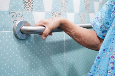 Asyalı yaşlı kadın banyoda güvenlik korkuluğu kullanıyor..