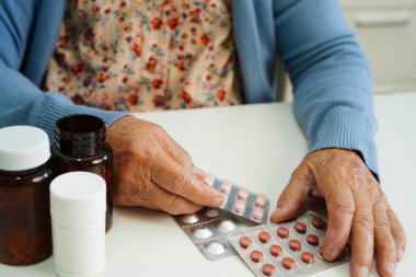 Asyalı yaşlı kadın bardakta suyla birlikte hap tutuyor. Sağlıklı, güçlü bir ilaç..